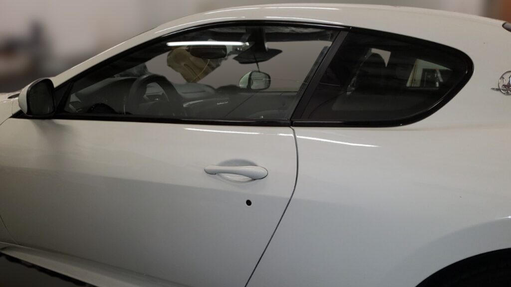 Professional window tinting installation on a car door in a Las Vegas shop.