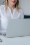 A woman working at a desk using a laptop and smartphone, exemplifying remote work.